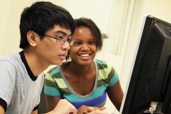 Two Honors College students facing a computer screen intently. 